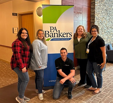 Group of Five Standing Next to PA Bankers Banner